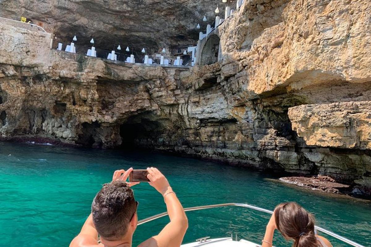 suda bir teknenin fotoğrafını çeken bir adam