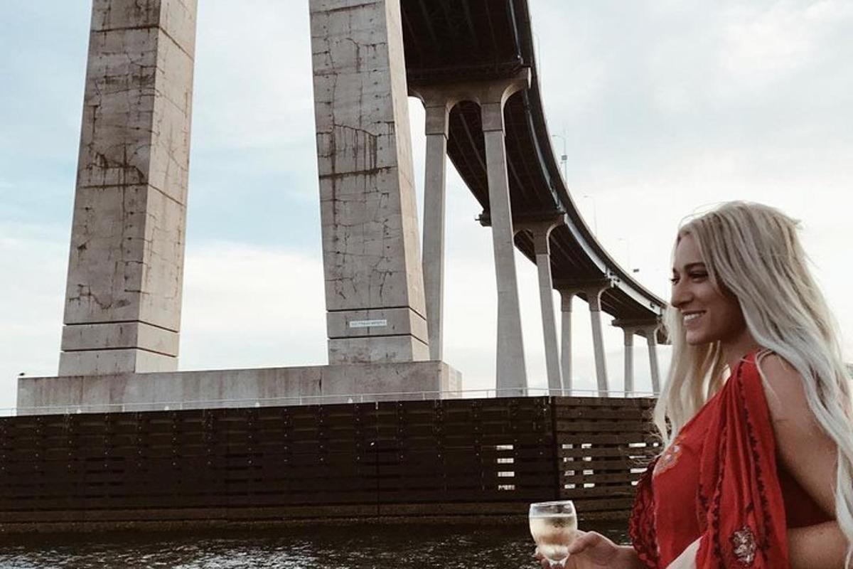 žena držící sklenici vína před mostem