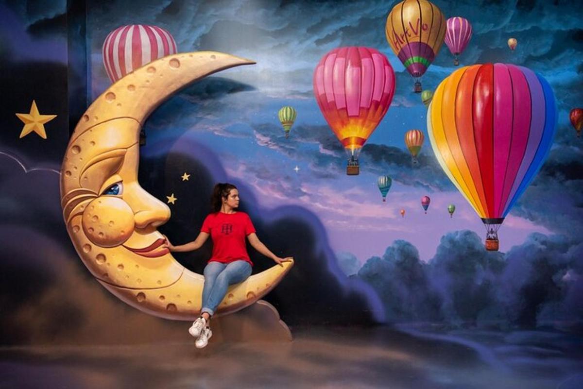 a woman sitting on a crescent moon with hot air balloons