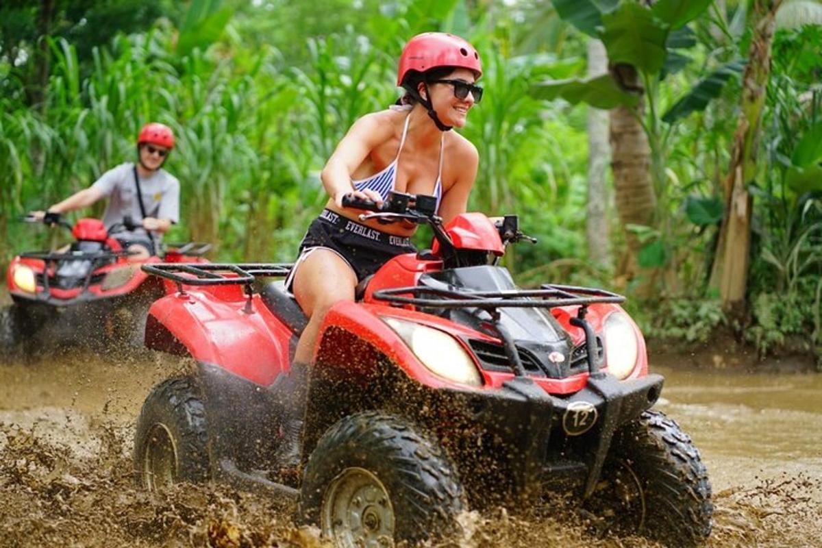 two people riding on atvs in the mud