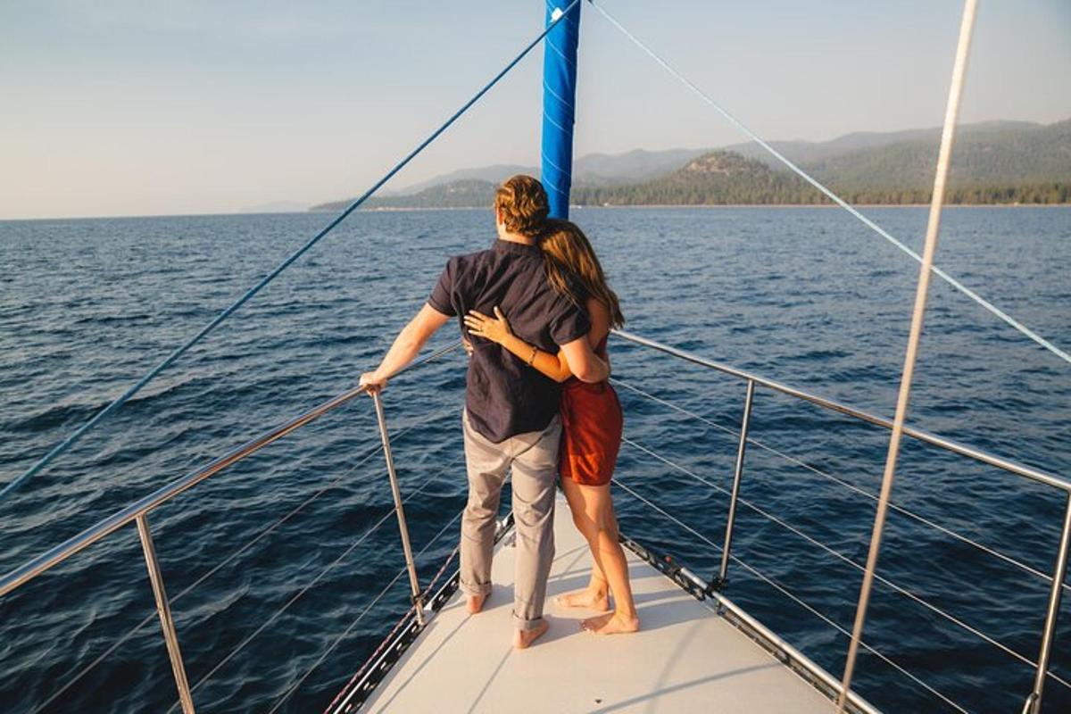 a man and woman standing on the bow of a sail boat