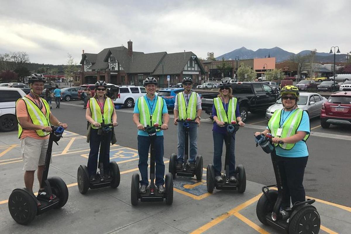 Grupa ludzi w kamizelkach bezpieczeństwa jadących na segwayach