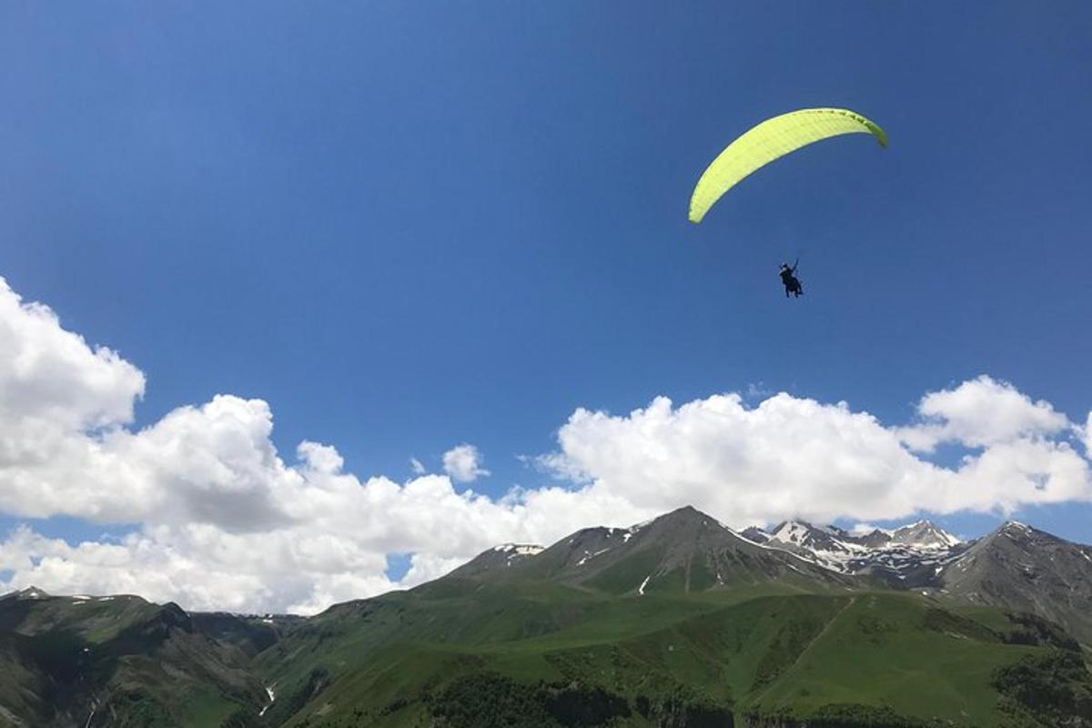 山の上をパラシュートで飛ぶ人