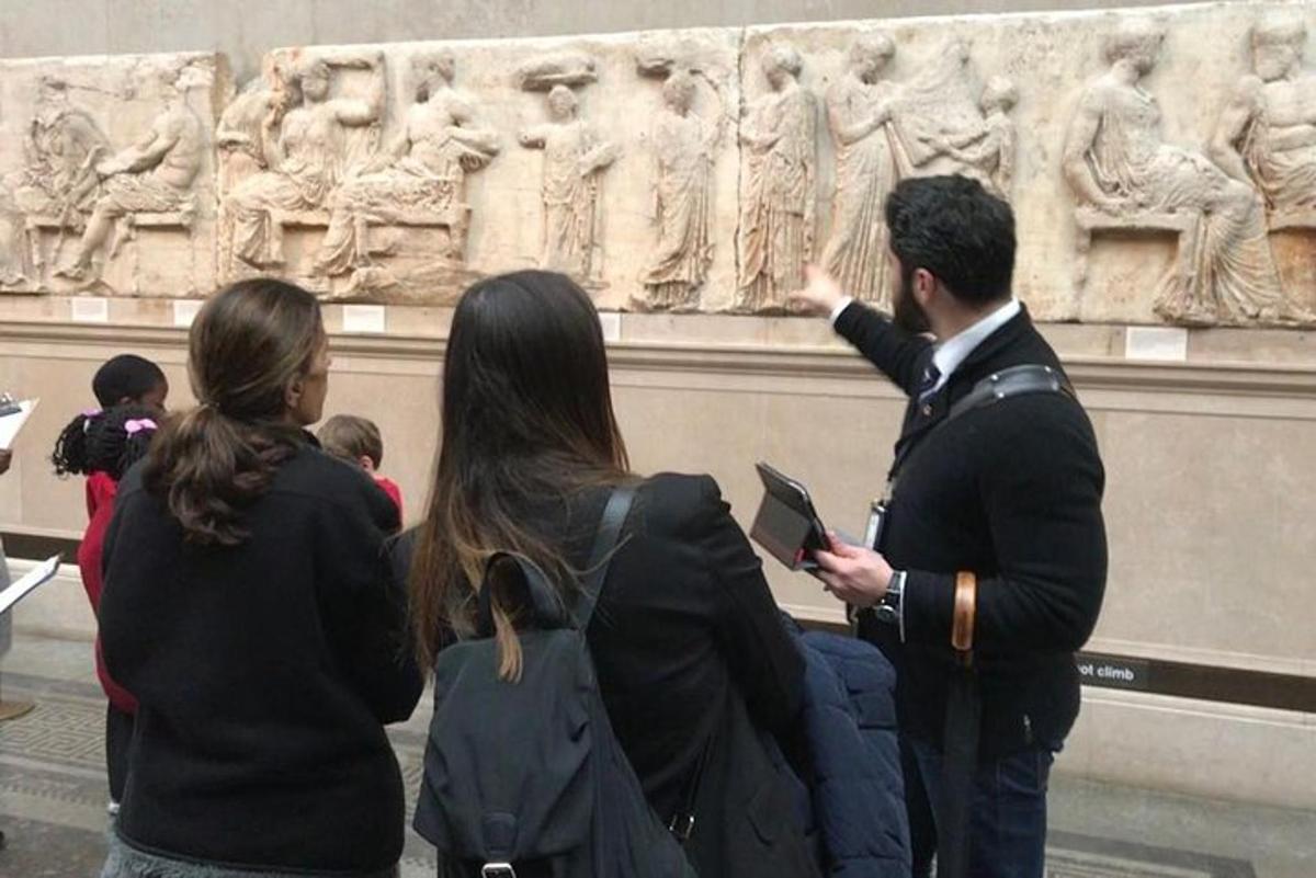 Un grupo de personas de pie frente a una escultura.