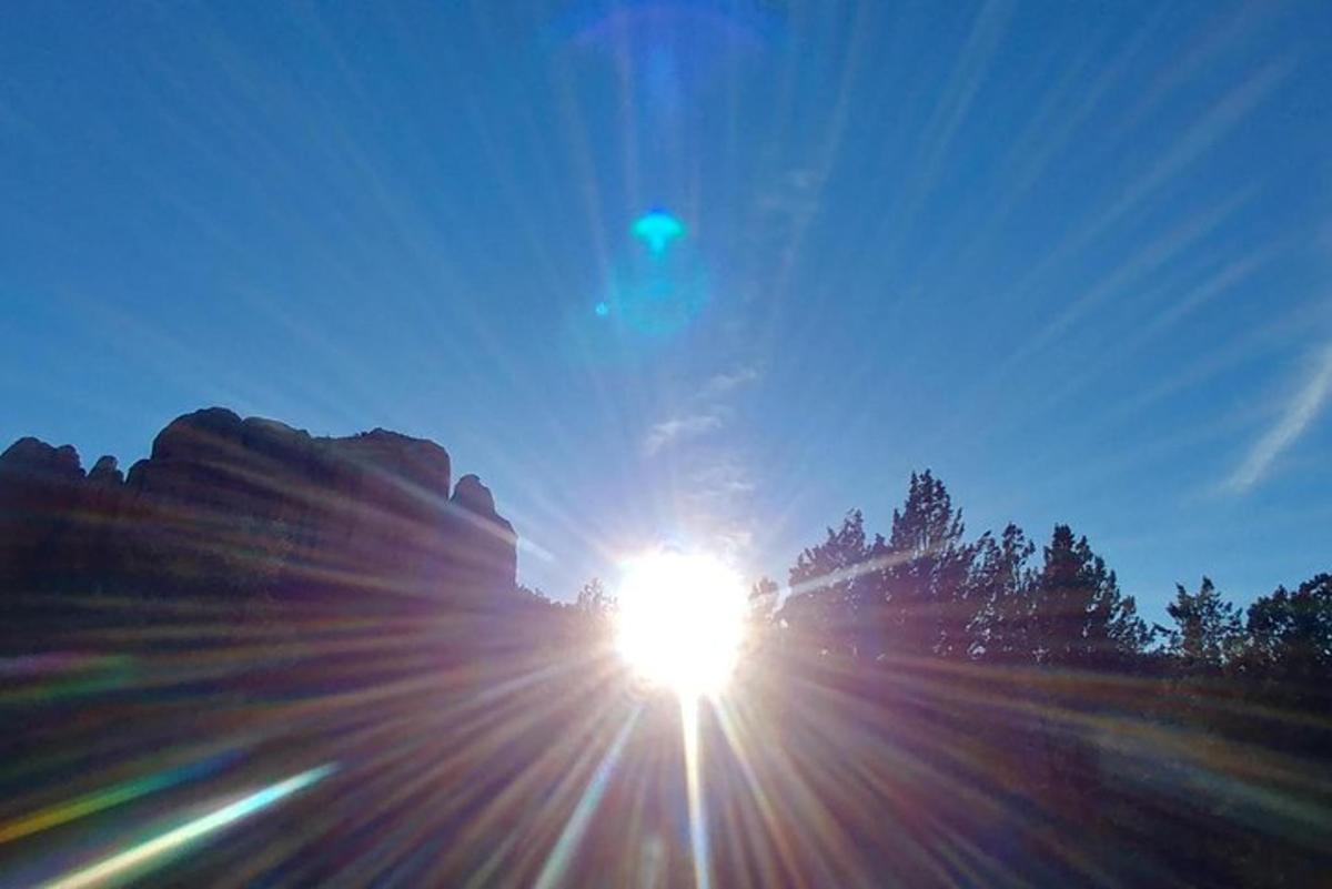 a sun shining in the sky over some trees