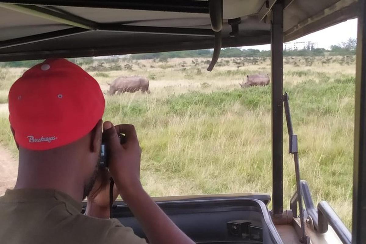a man taking a picture of elephants from a safari vehicle