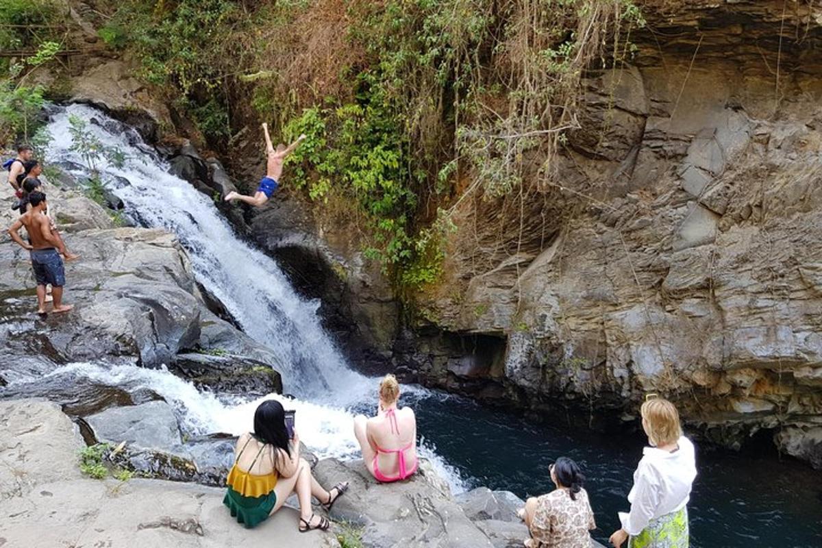 a group of people sitting on the rocks near a waterfall