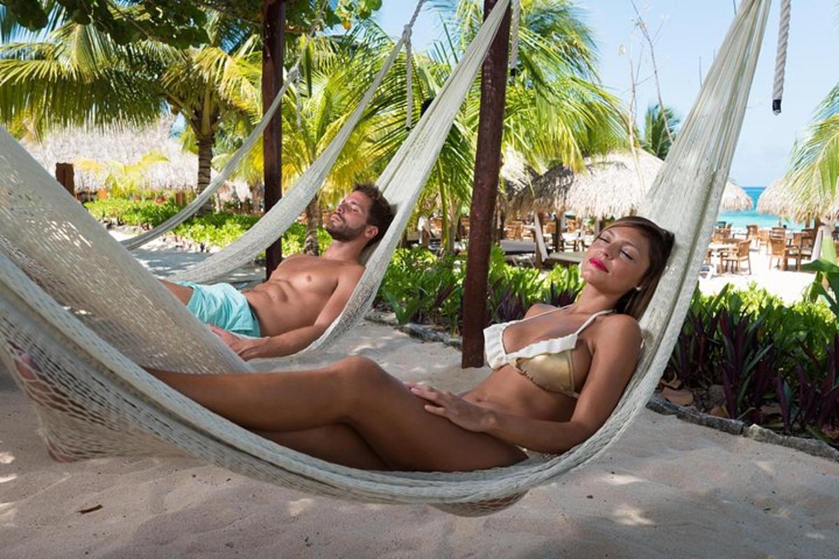 a man and woman laying in hammocks on the beach