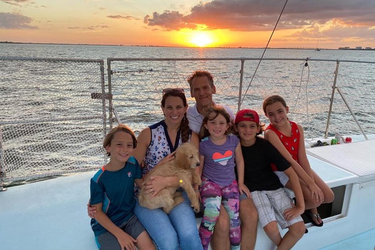 una família posant en un vaixell a la posta de sol