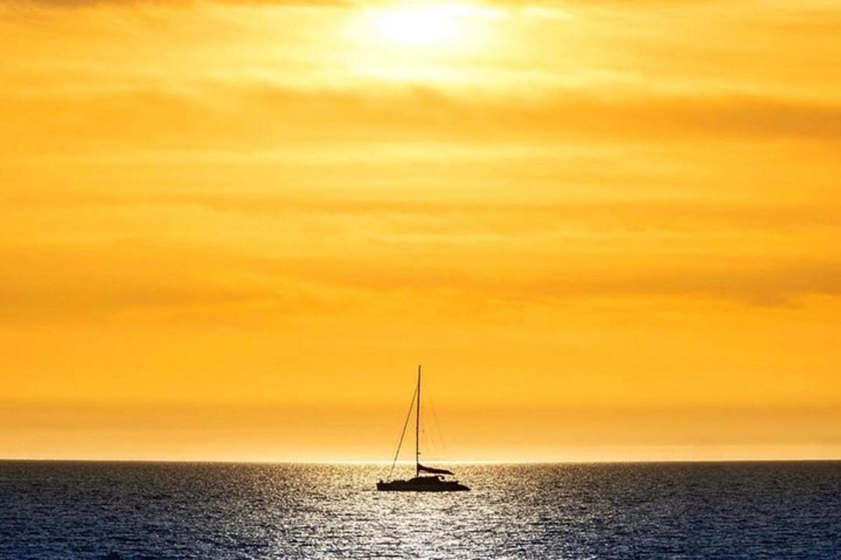 un veler a l'oceà sota un cel taronja