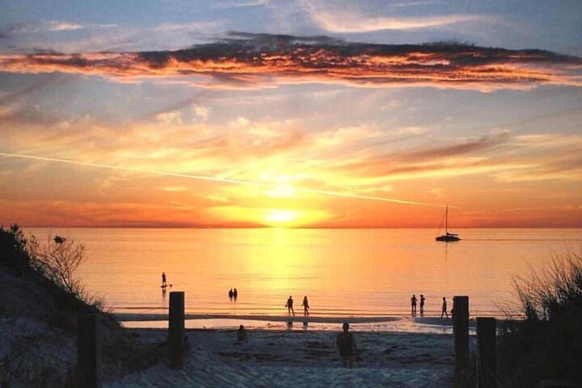 un grup de persones a la platja a la posta de sol