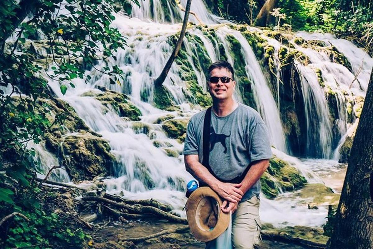 um homem parado em frente a uma cachoeira