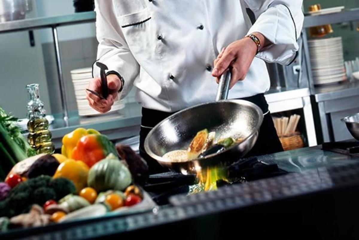 a chef in a kitchen preparing food in a wok