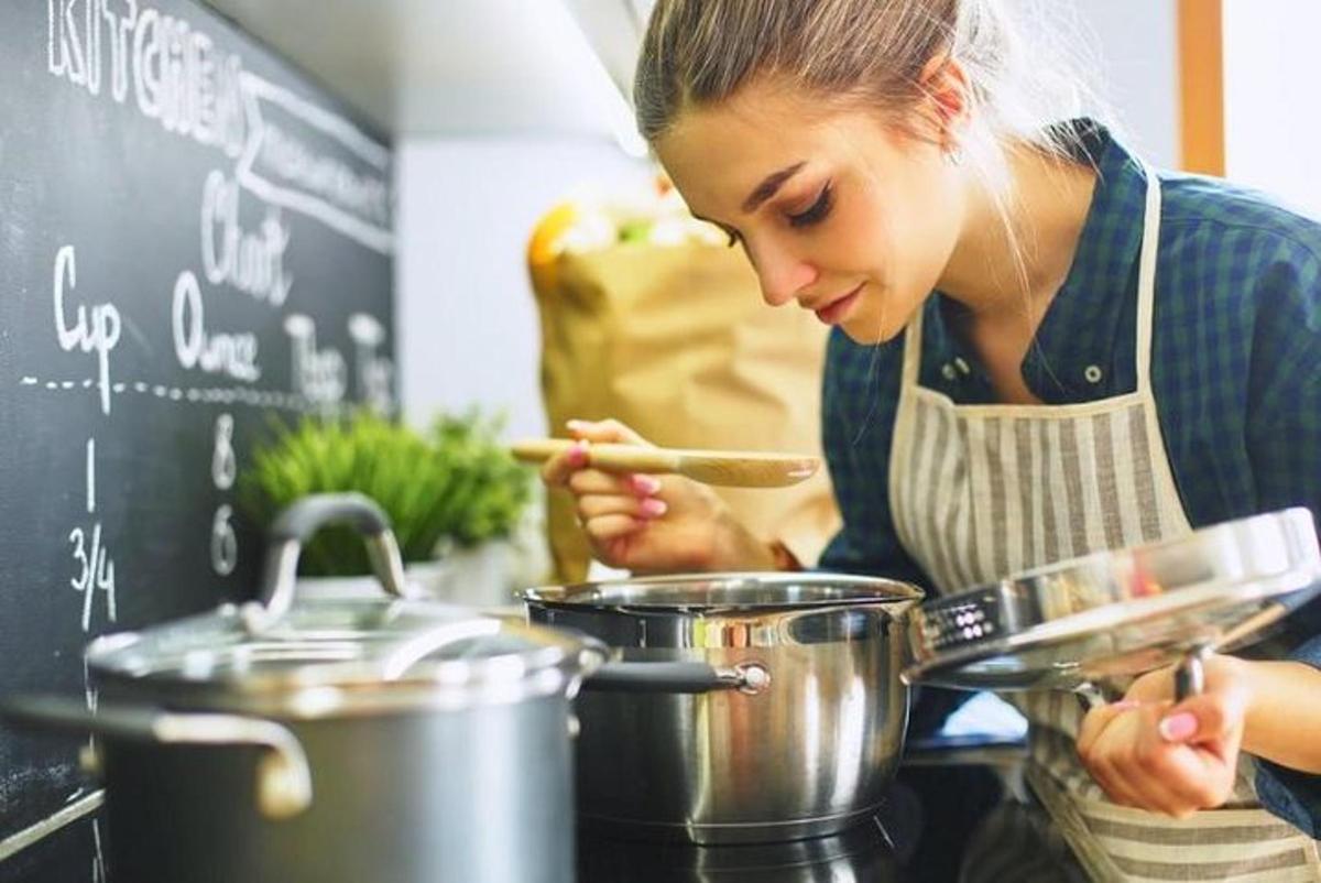 a woman in a kitchen stirring pots and pans