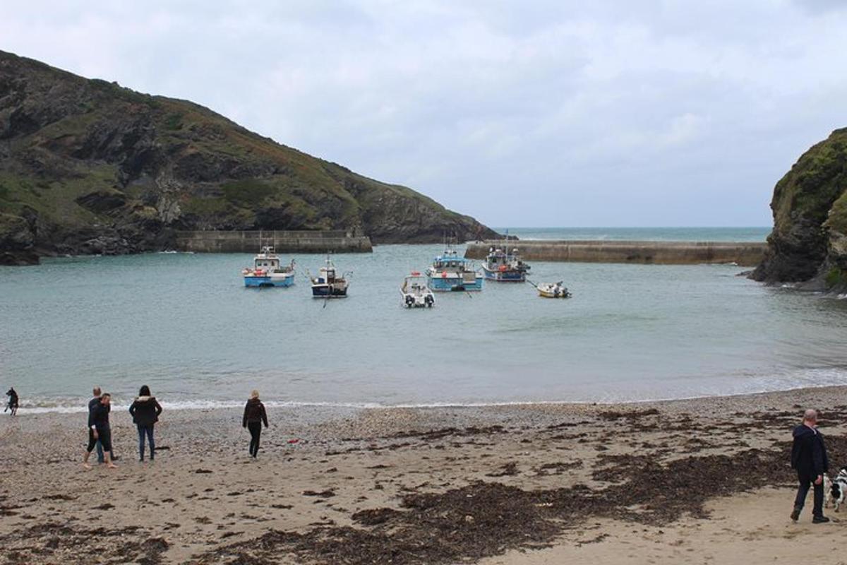 a group of people walking on a beach with boats in the water