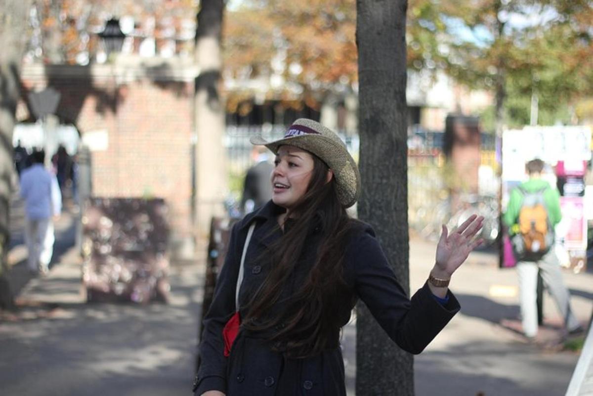 Una mujer con sombrero parada junto a un árbol.