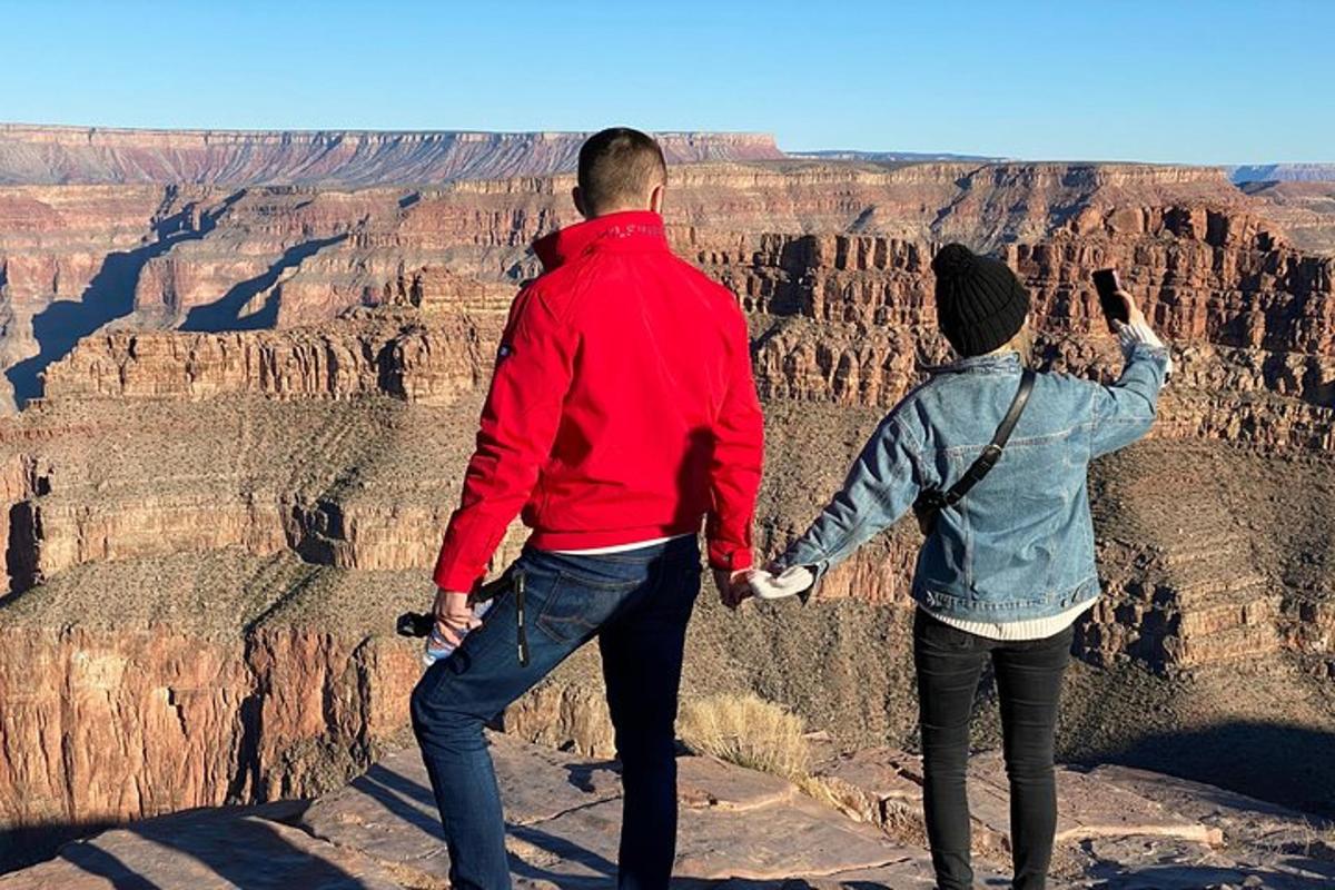 two people holding hands while standing at the grand canyon