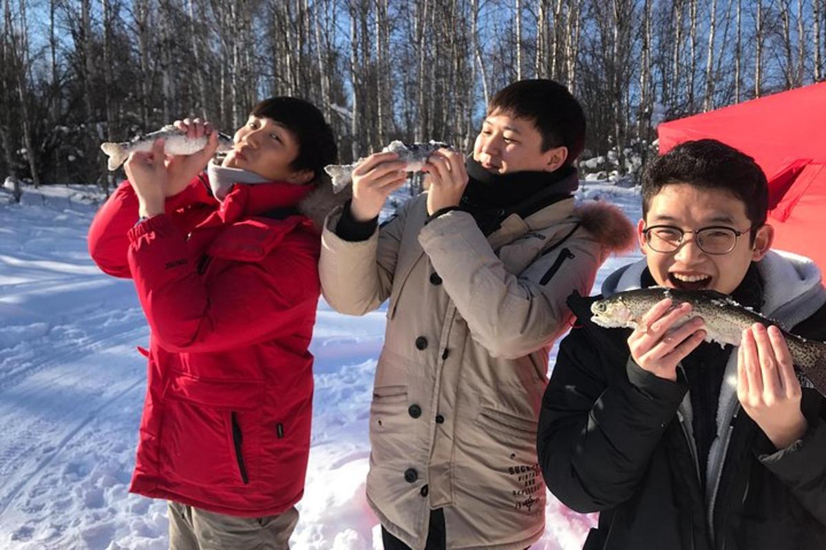 Un grupo de personas sosteniendo peces en la nieve.