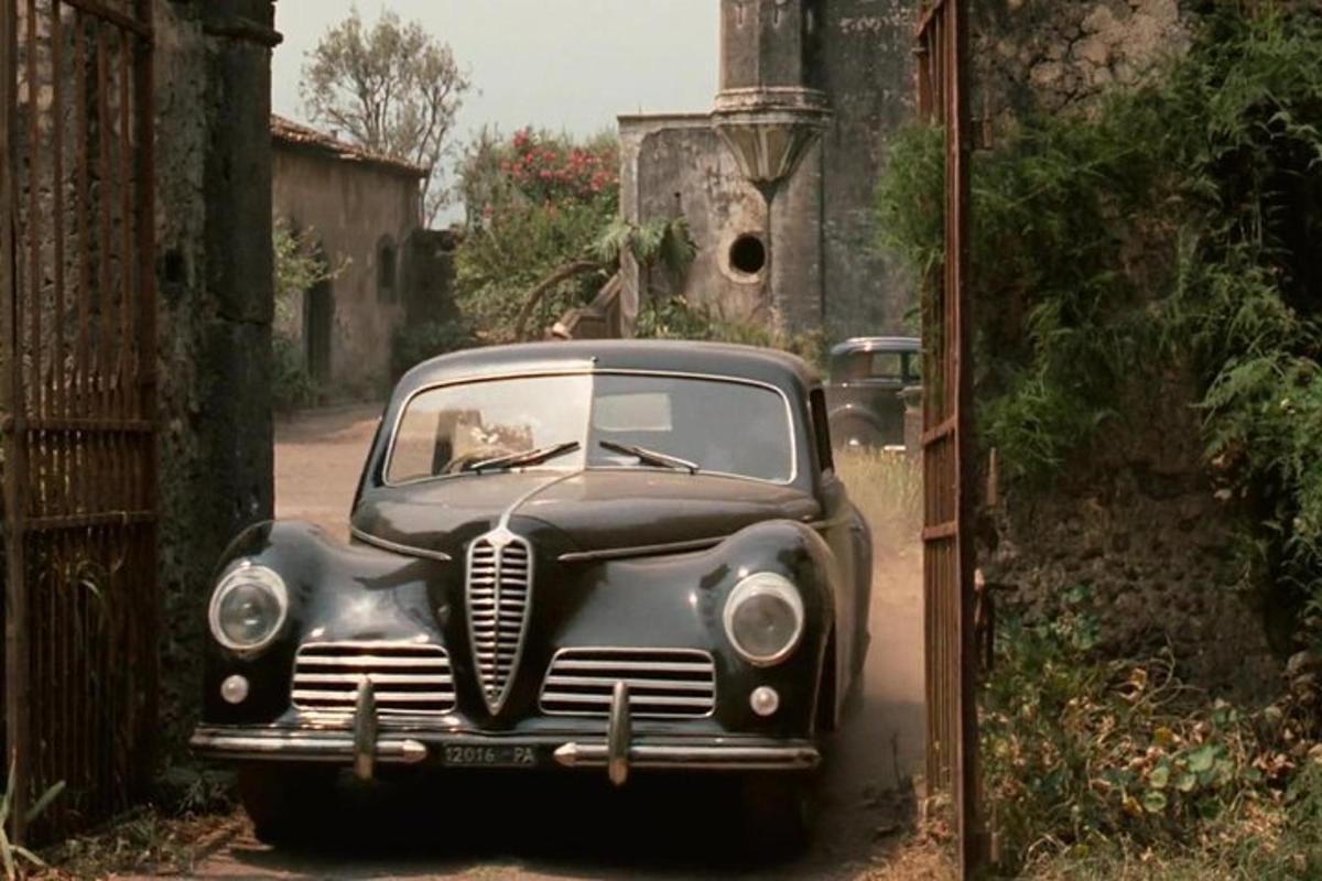 an old black car parked in an alley