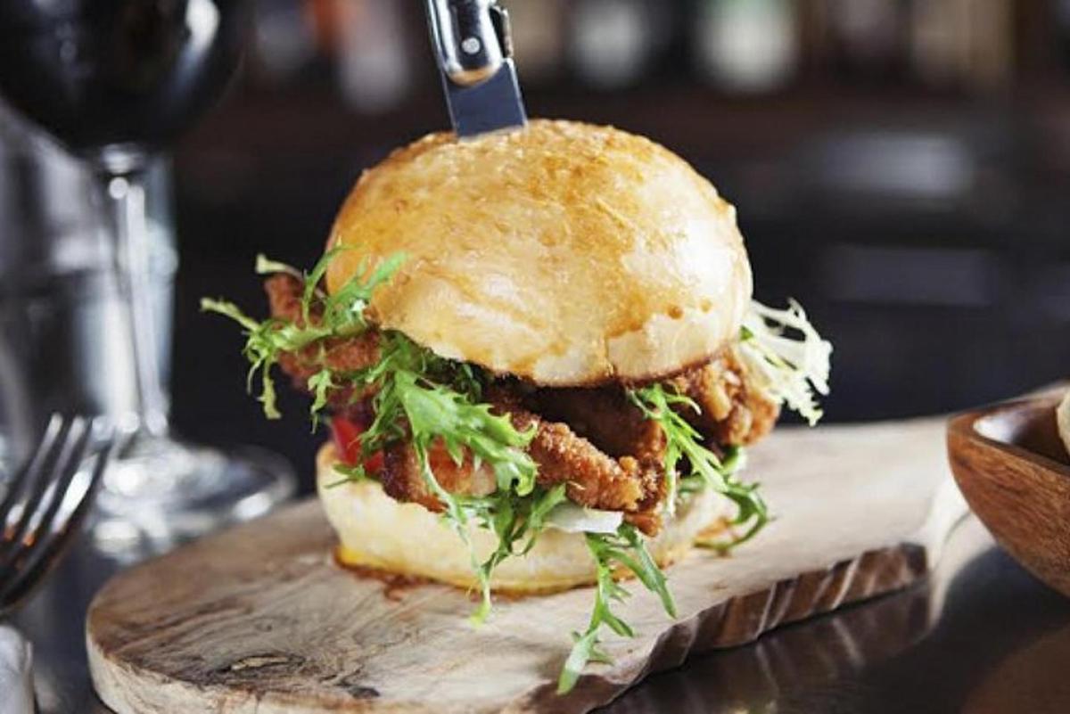 un panino al pollo su un piatto di legno con un bicchiere di vino