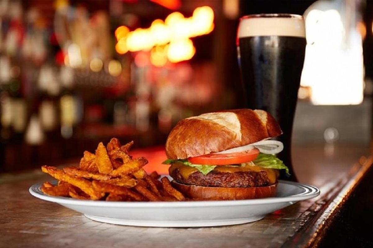 un panino e patatine fritte su un piatto con una pinta di birra