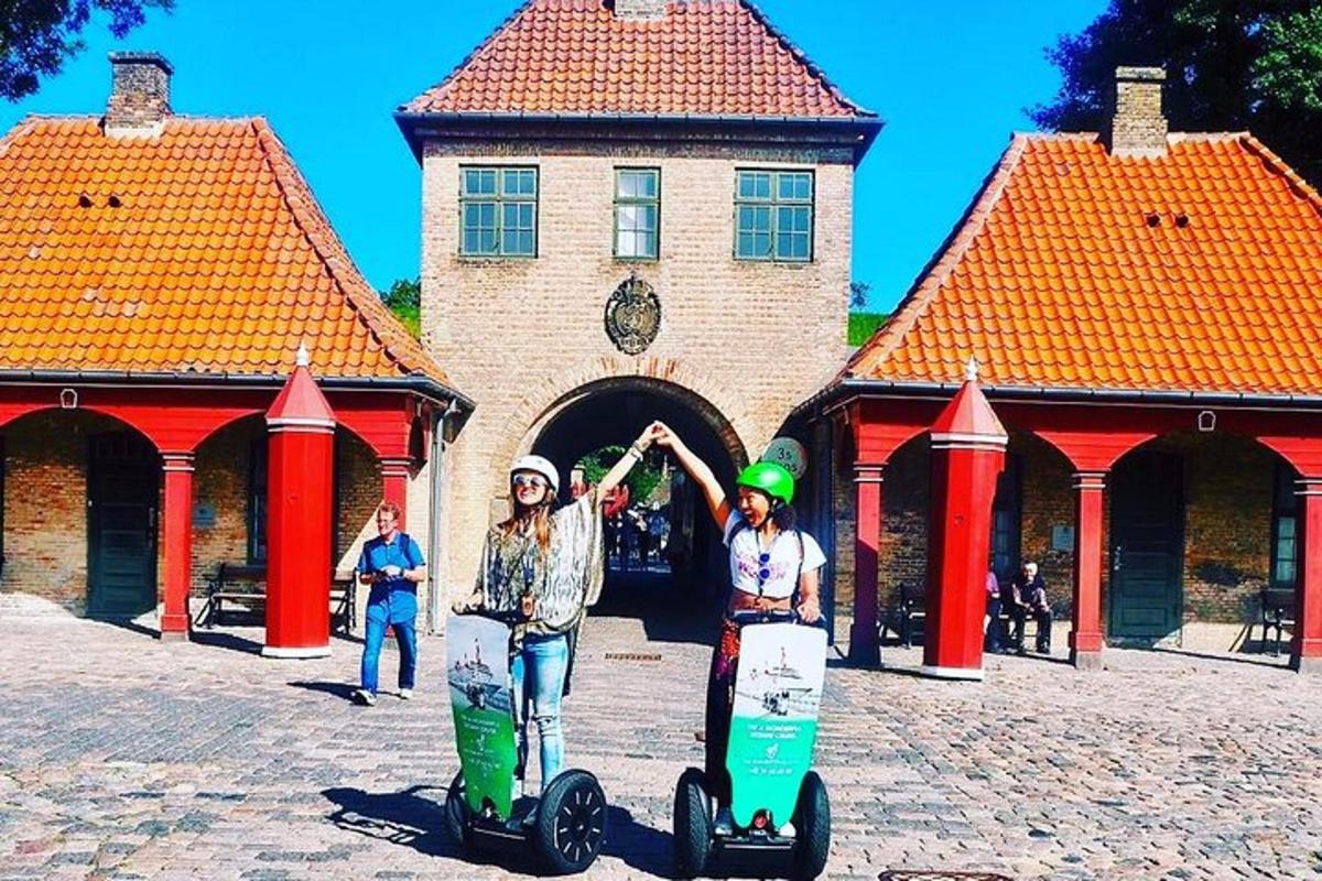 Dos chicas están paradas con patinetas frente a un edificio.