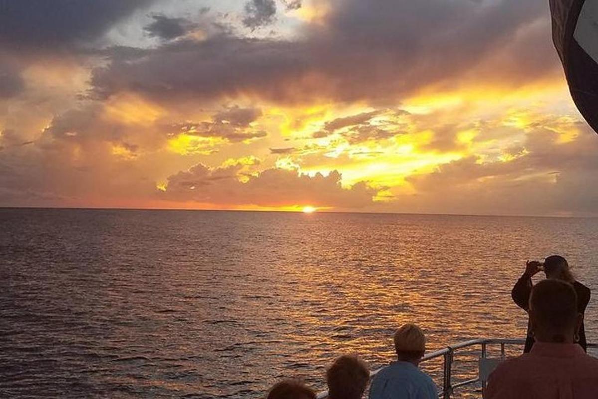 a group of people on a boat looking at the sunset