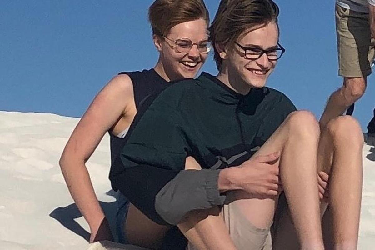 two people sitting in the sand on the beach