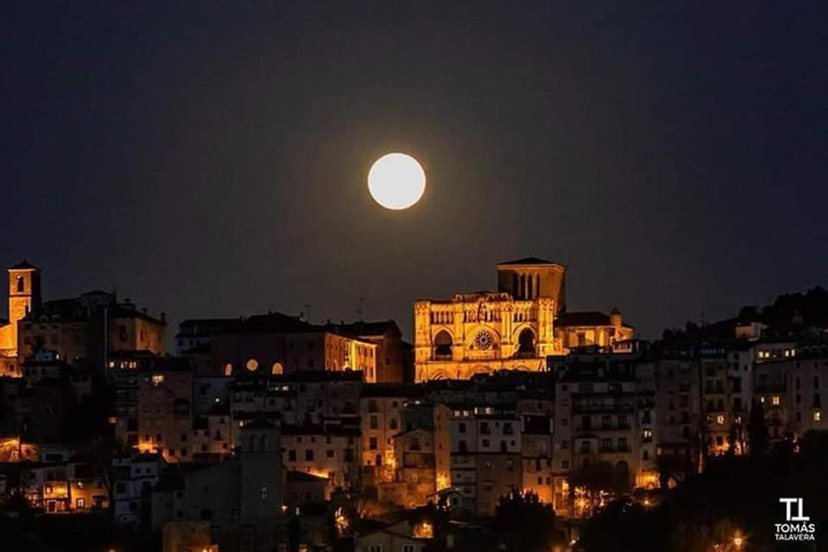 una luna piena che sorge su una città di notte