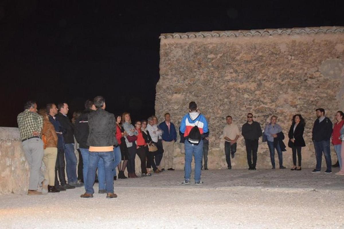 un gruppo di persone in piedi attorno a un muro di notte