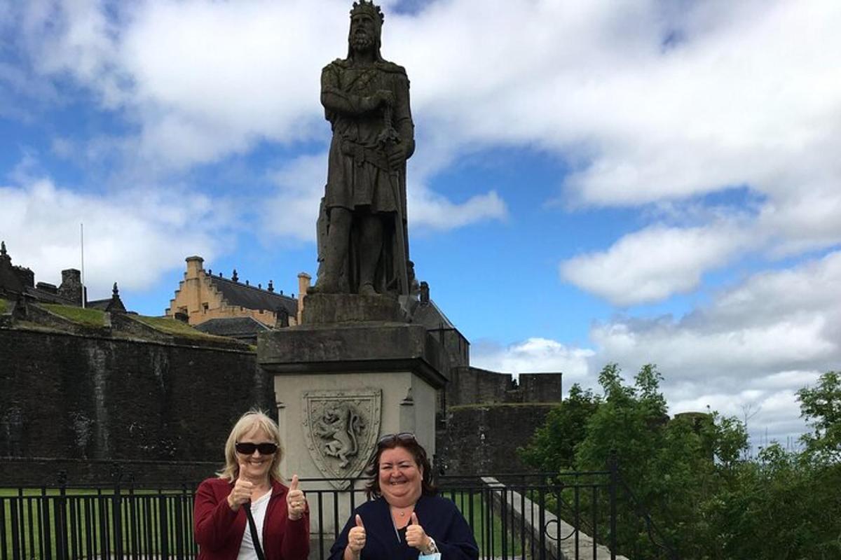 two women standing in front of a statue