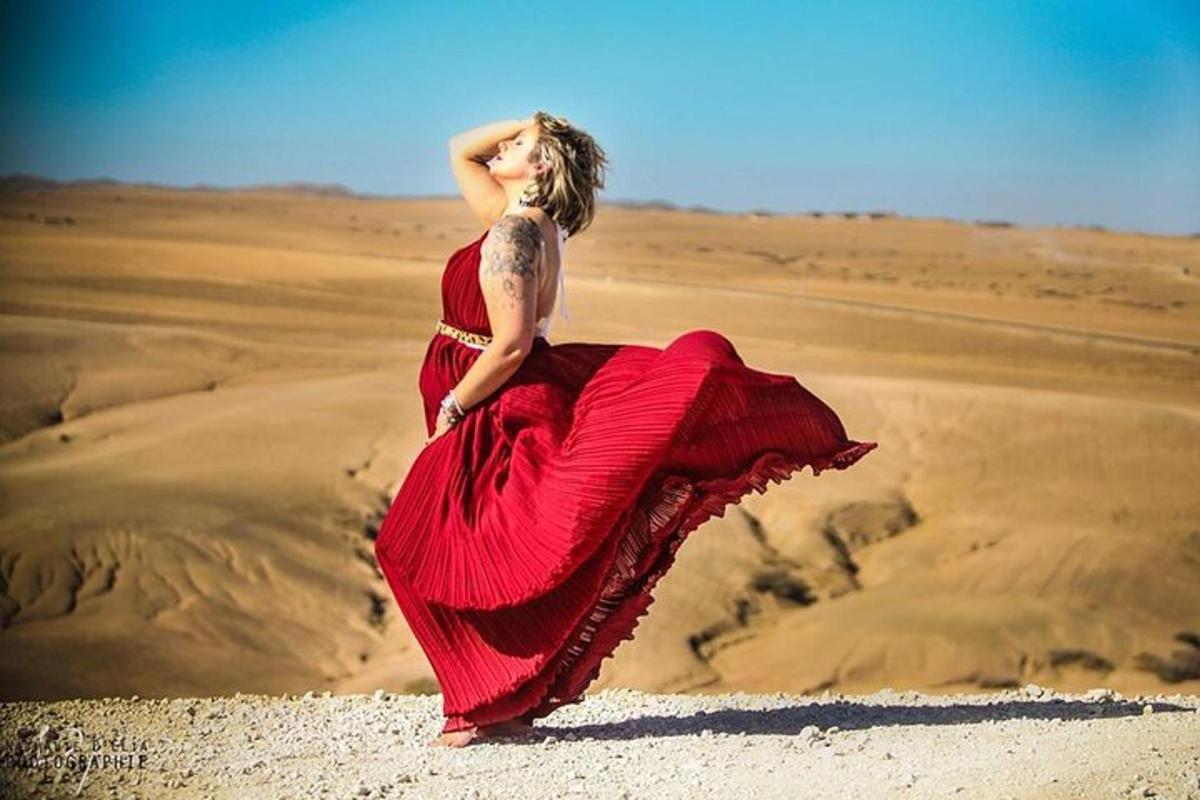 Una mujer con un vestido rojo parada en el desierto