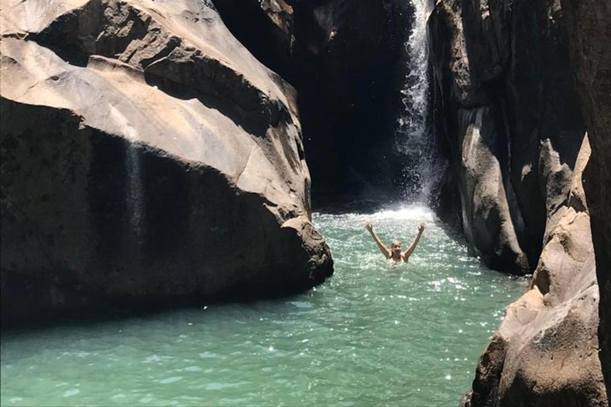a person in the water in front of a waterfall