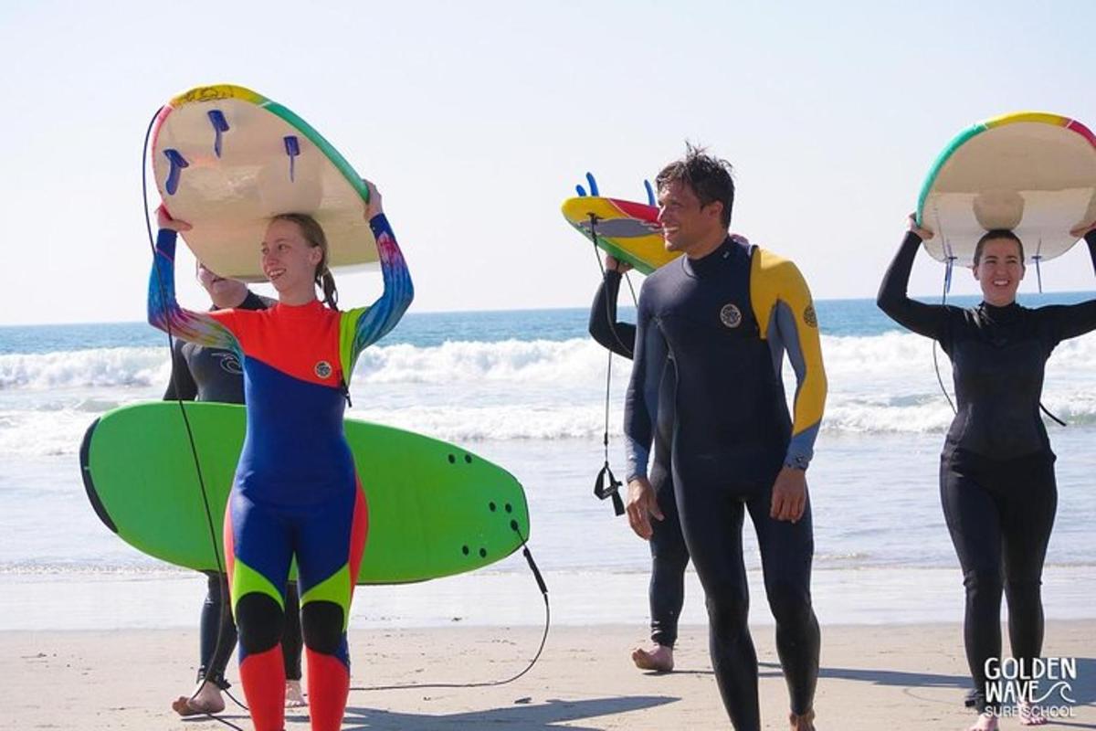 un groupe de personnes marchant sur la plage avec des planches de surf