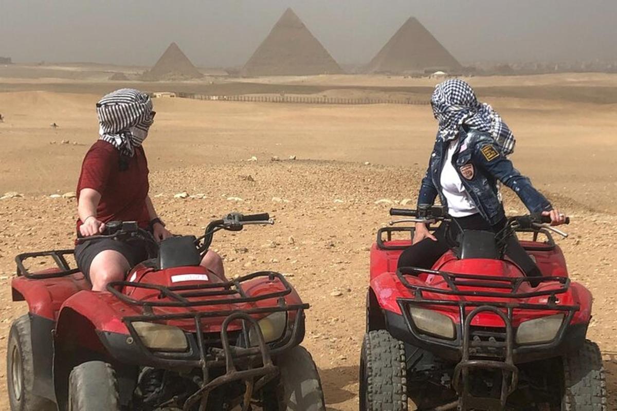 two people riding atvs in front of the pyramids