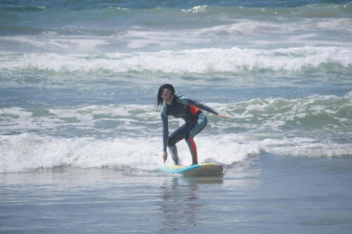 una noia jove cavalcant una onada sobre una taula de surf a l'oceà