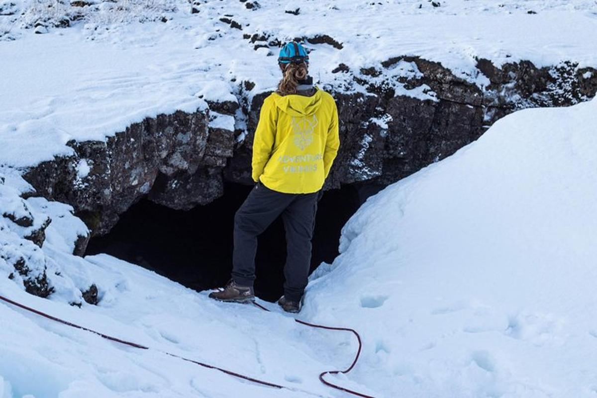 uma mulher parada em frente a uma caverna na neve