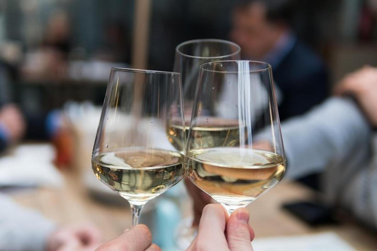 two people holding up glasses of white wine