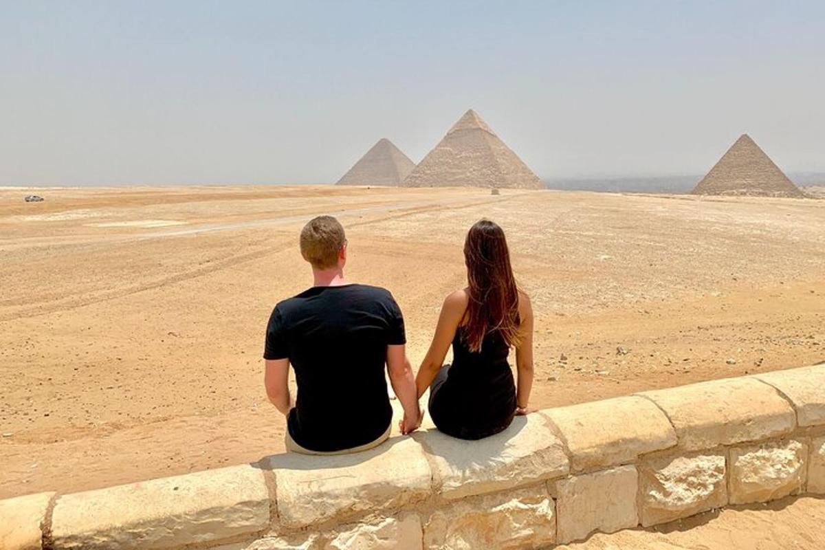 muž a žena sedící na zdi a dívající se na pyramidy