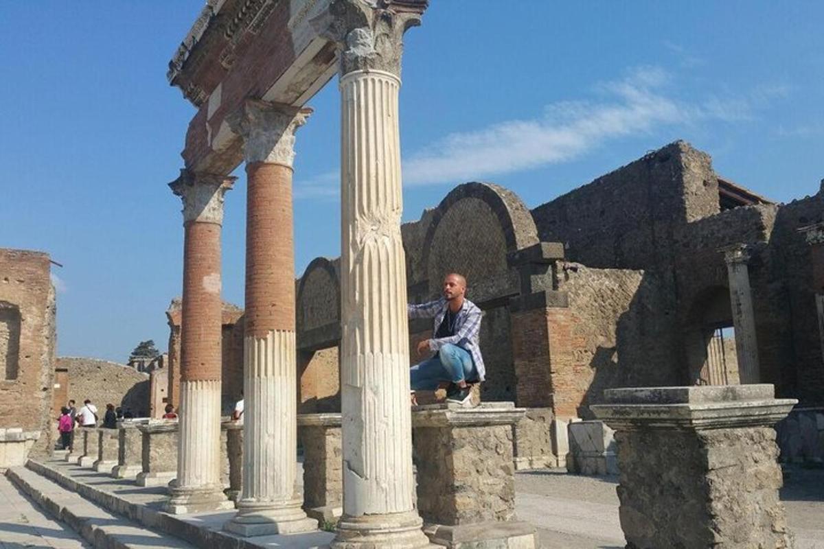 Un hombre sentado en una columna de un edificio.