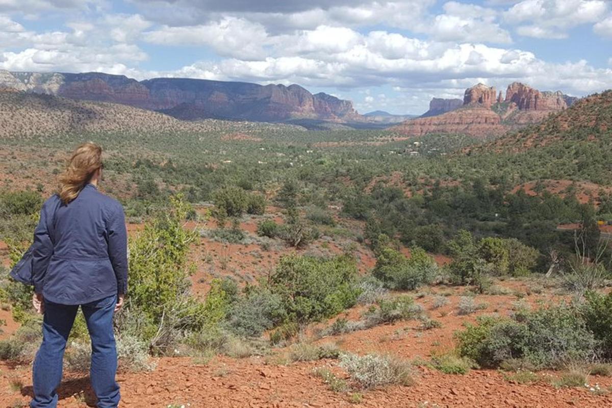 Una mujer parada en la cima de una colina con vistas a un cañón.