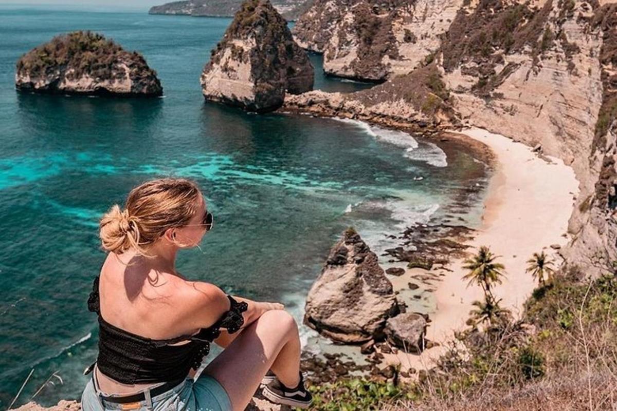 ženska, ki sedi na pečini s pogledom na plažo