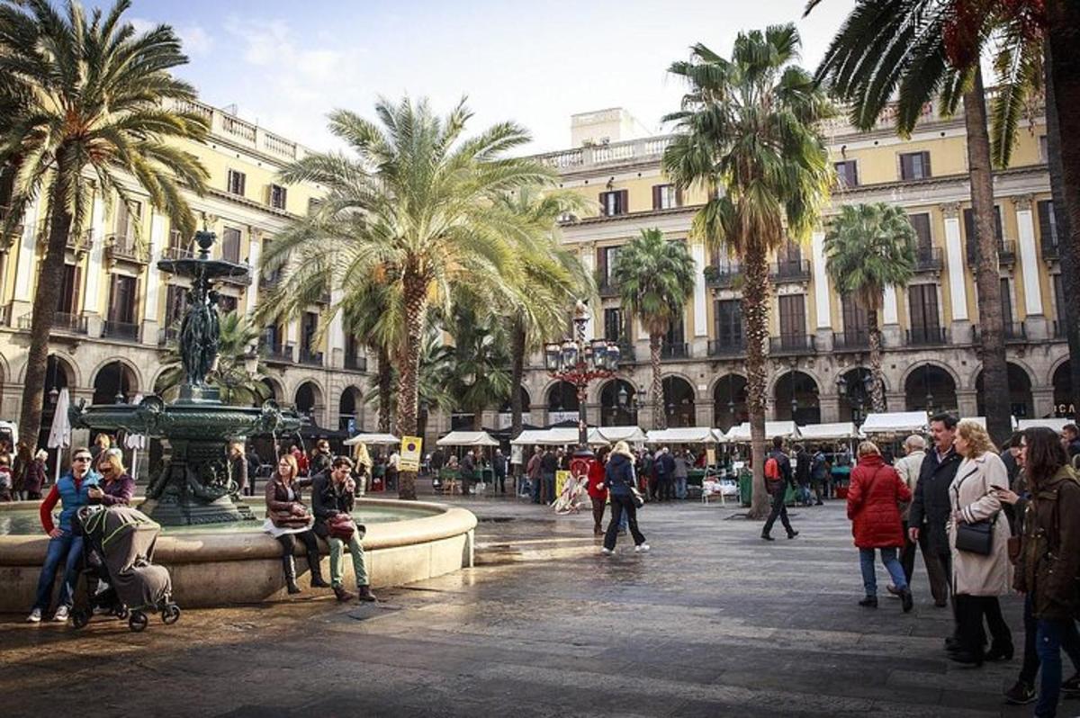 a group of people walking around a fountain in a city