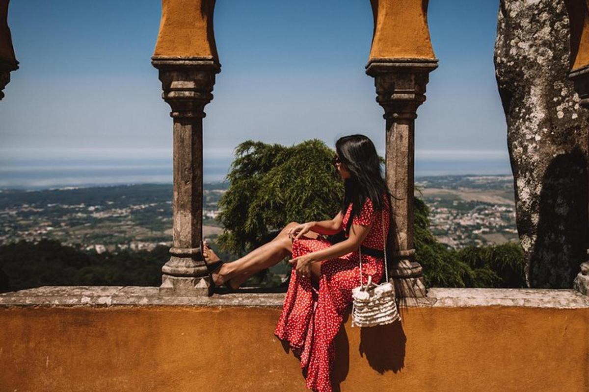 a woman in a red dress sitting on a wall