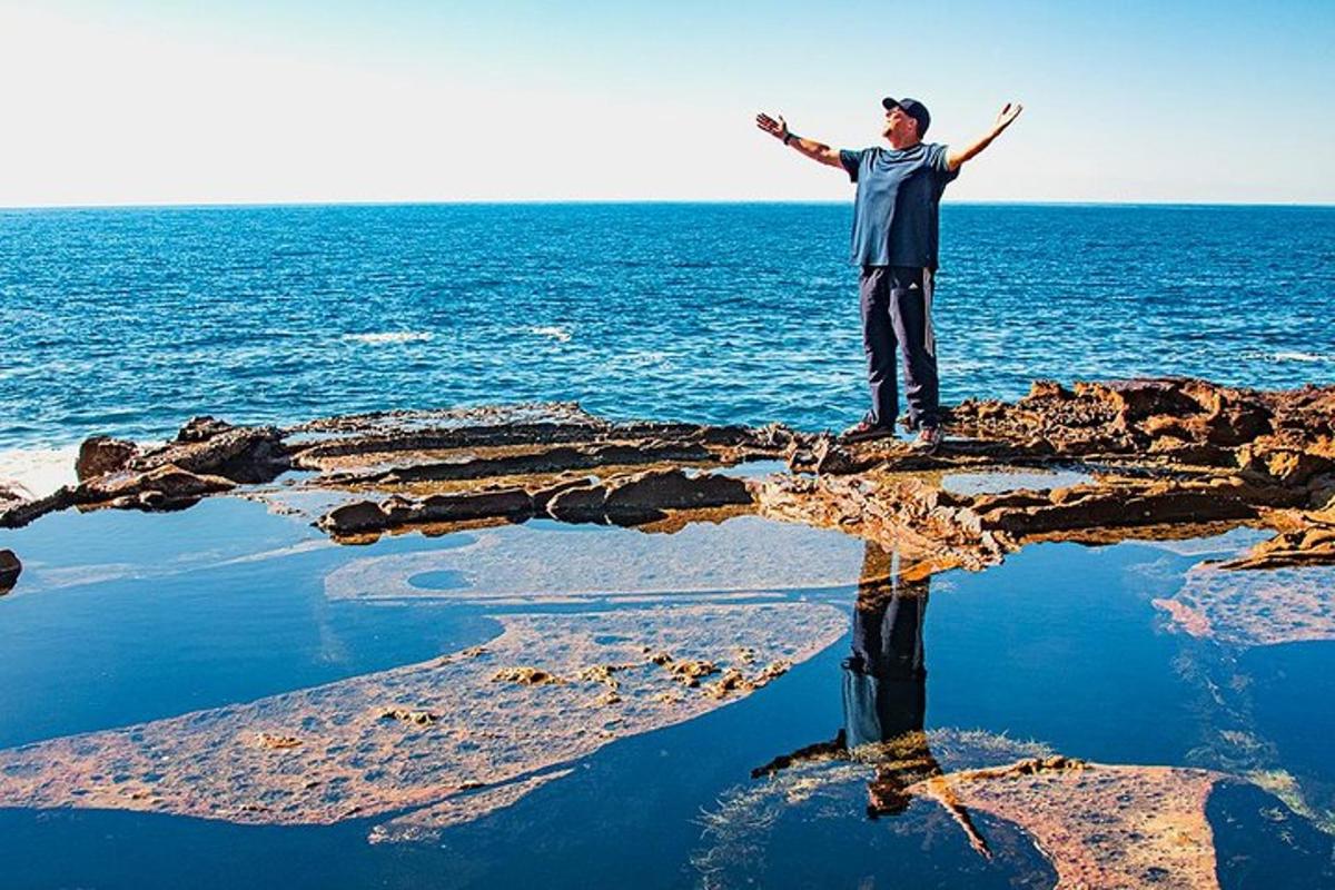 un uomo in piedi su una roccia nell'oceano