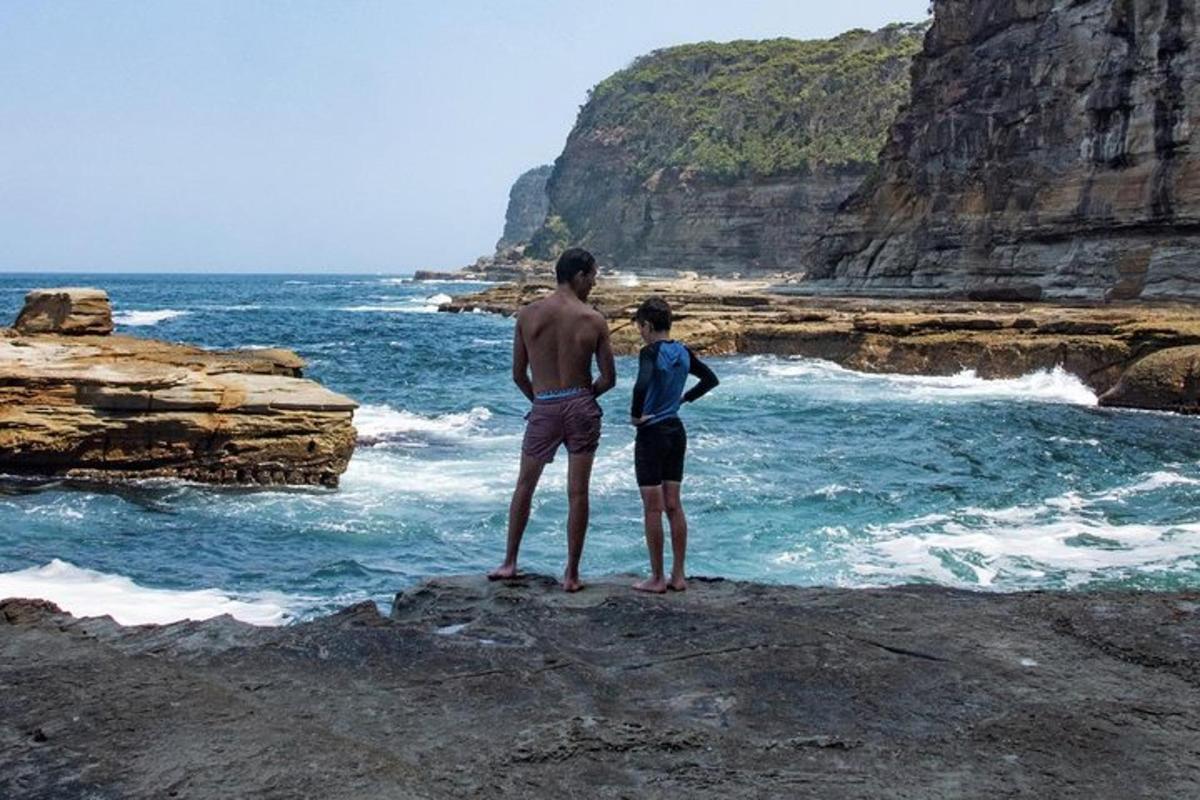 un uomo e una donna in piedi sulle rocce vicino all'oceano