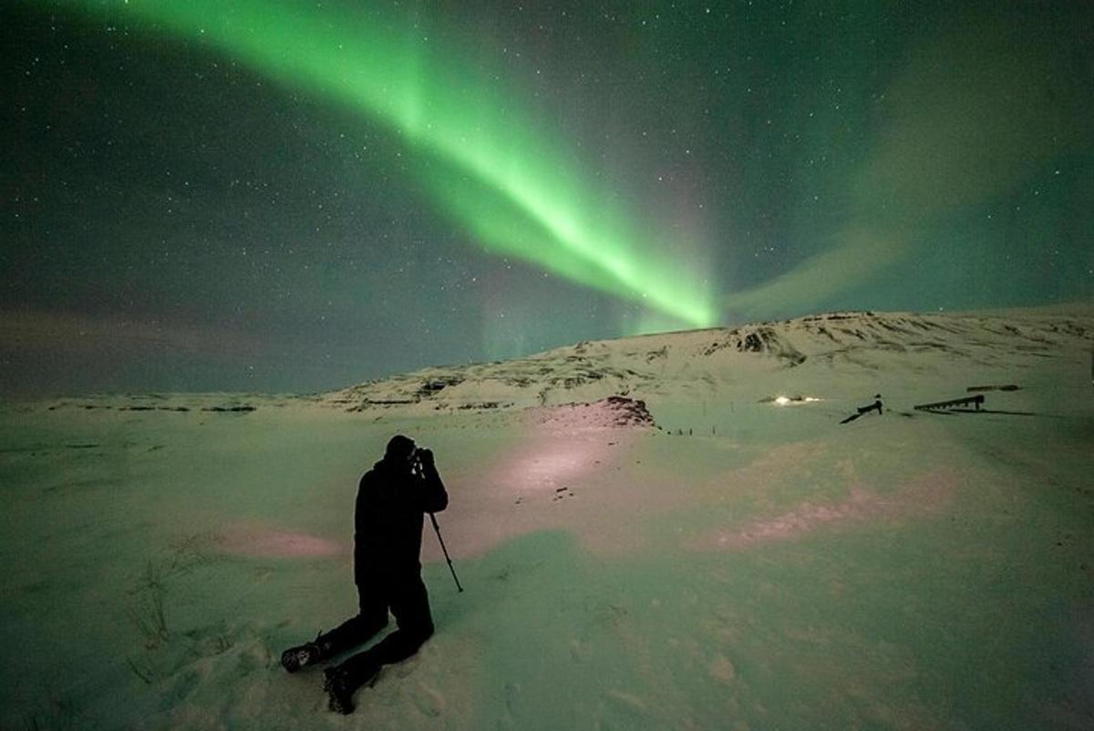 una persona sugli sci nella neve sotto l'aurora boreale