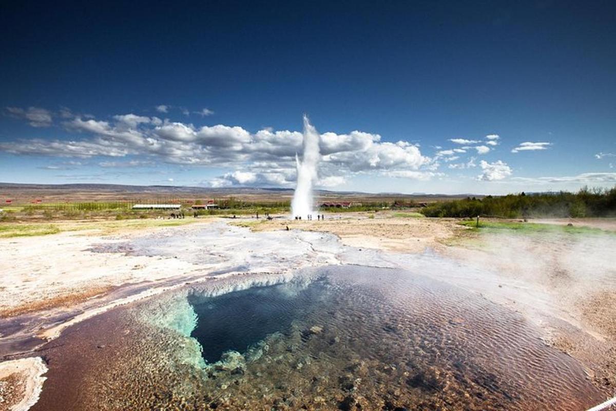 a geyser in the middle of a field with a pool of water