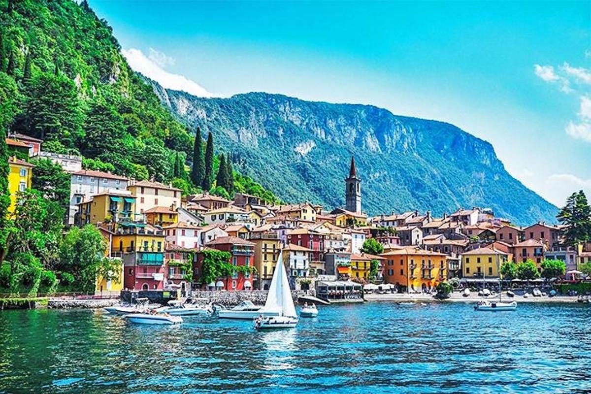 uma pequena cidade em um lago com um barco à vela