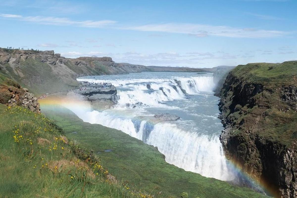 una cascata con un arcobaleno di fronte a un fiume